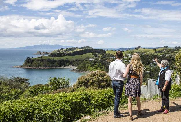 Guide showing clients the view overlooking costal area and beaches on Waiheke Island