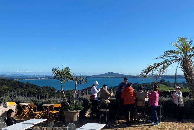 Guests wine tasting with stunning scenic view behind them